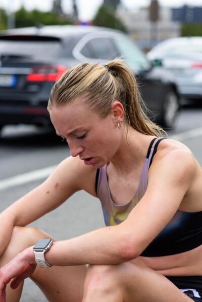 Injured runner sitting on track holding knee in pain
